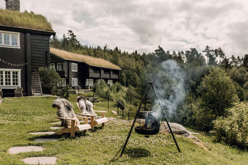 Storfjord Hotel dark wood Norwegian farmhouse with grass roof and outdoor fire, Sunnmøre