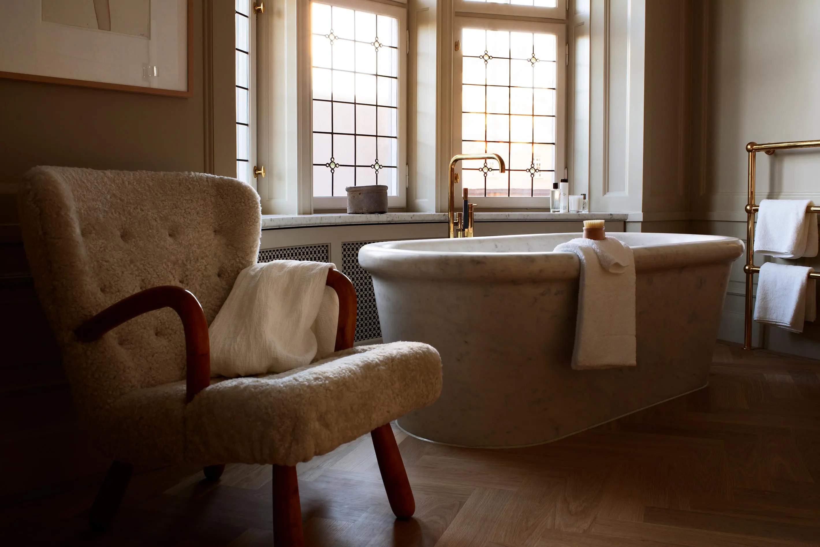 Ett Hem Stockholm marble freestanding bathtub with sheepskin chair, leaded glass windows, herringbone floor