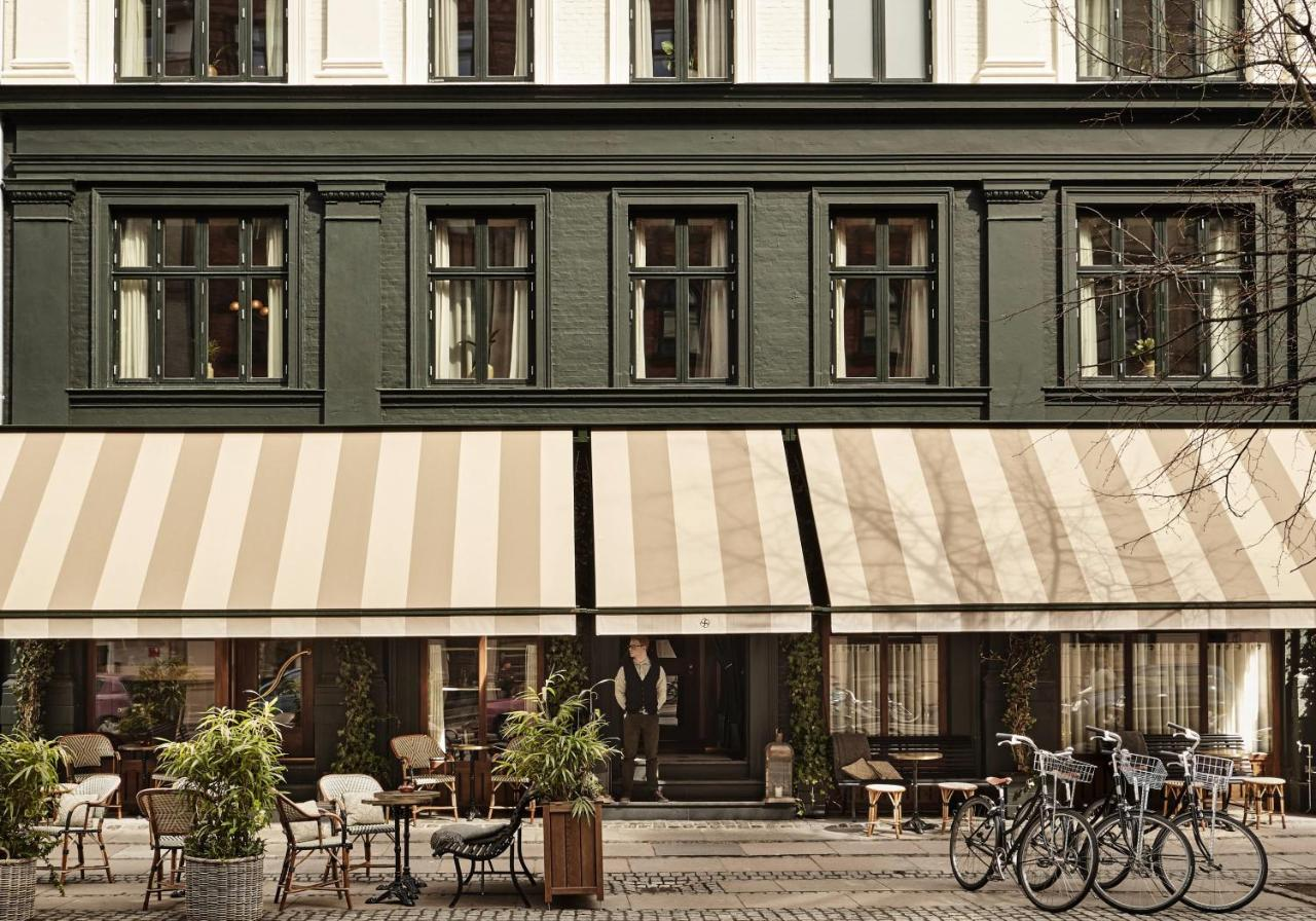 Hotel Sanders Copenhagen dark green facade with striped awning, outdoor terrace, bicycles