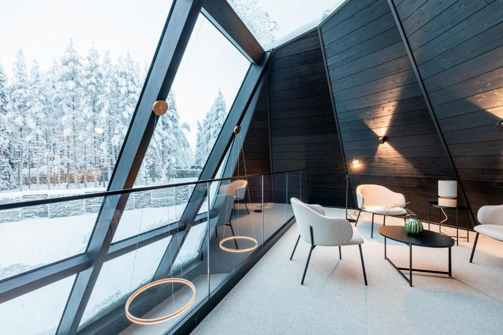 Arctic TreeHouse Hotel Finland black A-frame cabin interior with floor-to-ceiling glass, snowy forest