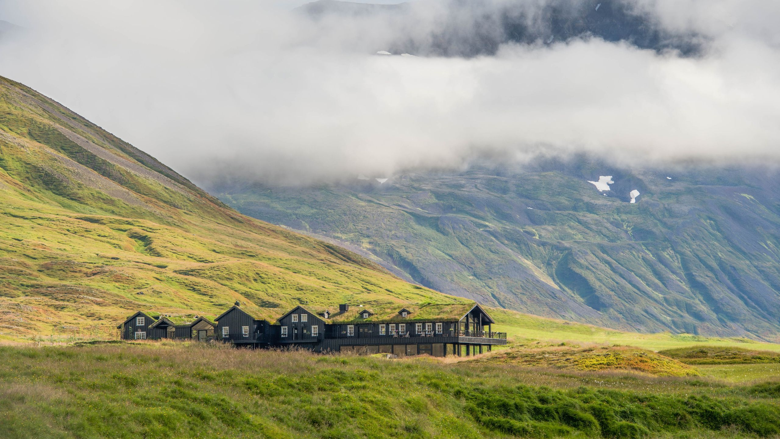 Deplar Farm Iceland long dark farmhouse with grass roof in Icelandic valley, mountains and clouds