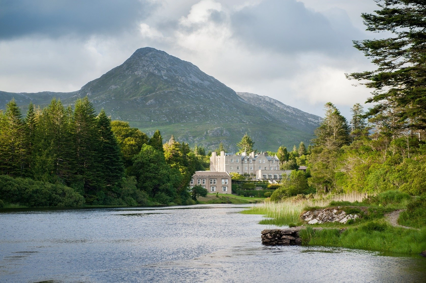 Ballynahinch Castle reflected in the river with the Twelve Bens mountain range, Connemara