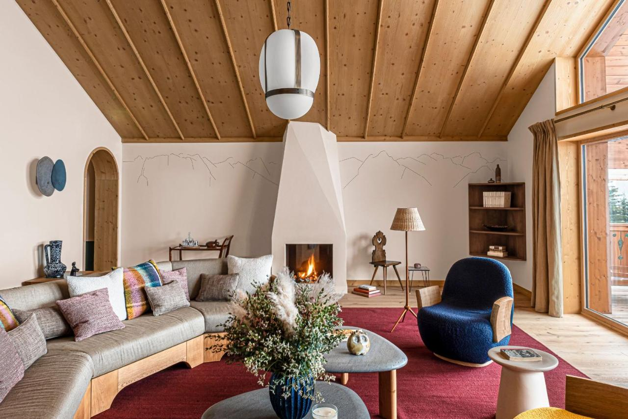 Le Coucou Méribel chalet living room with vaulted pine ceiling, white plaster fireplace, burgundy rug