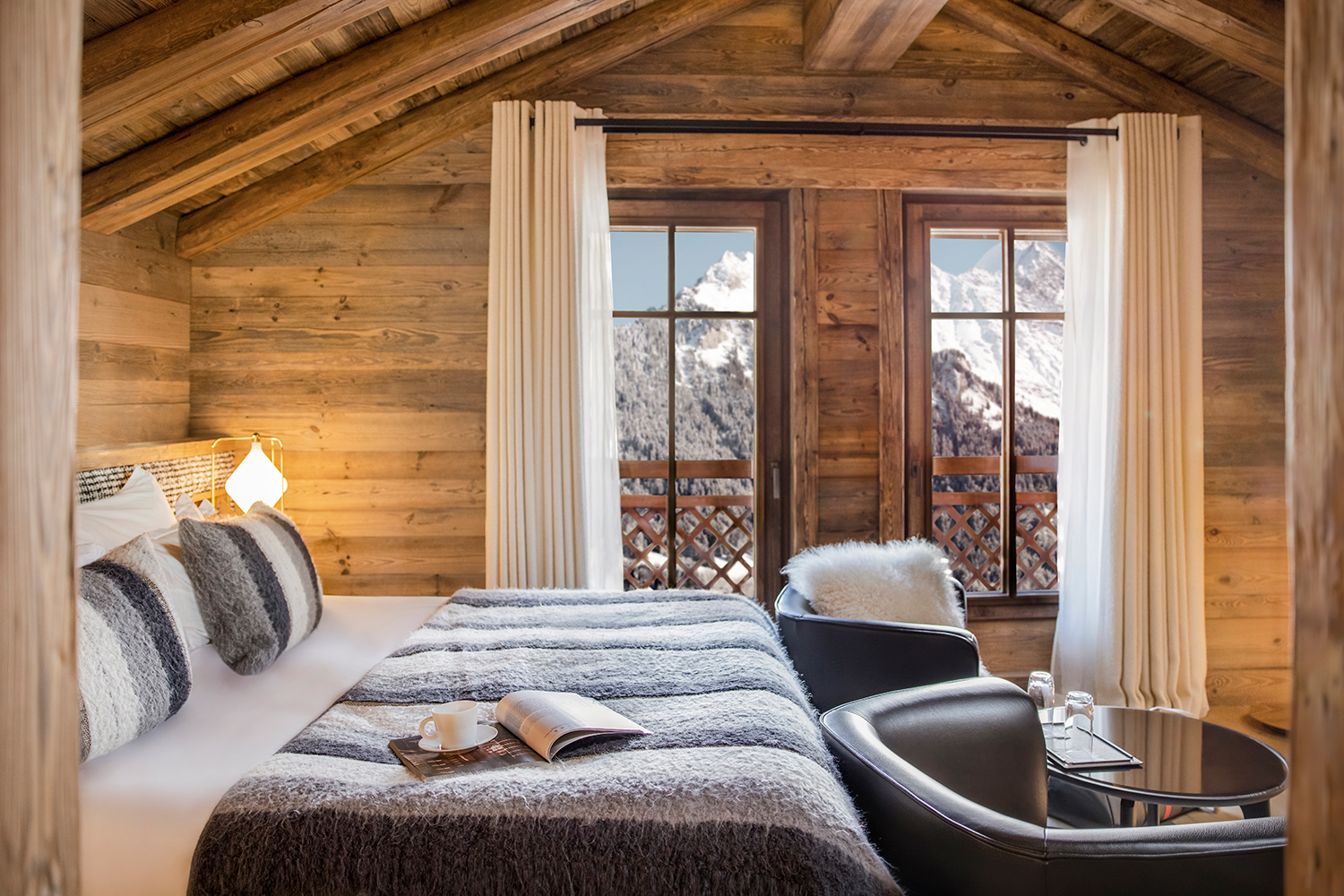 Portetta Courchevel cozy alpine bedroom with exposed timber ceiling, mountain view, fur throws